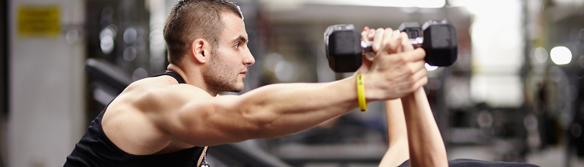 Personal trainer helping woman working with heavy dumbbells